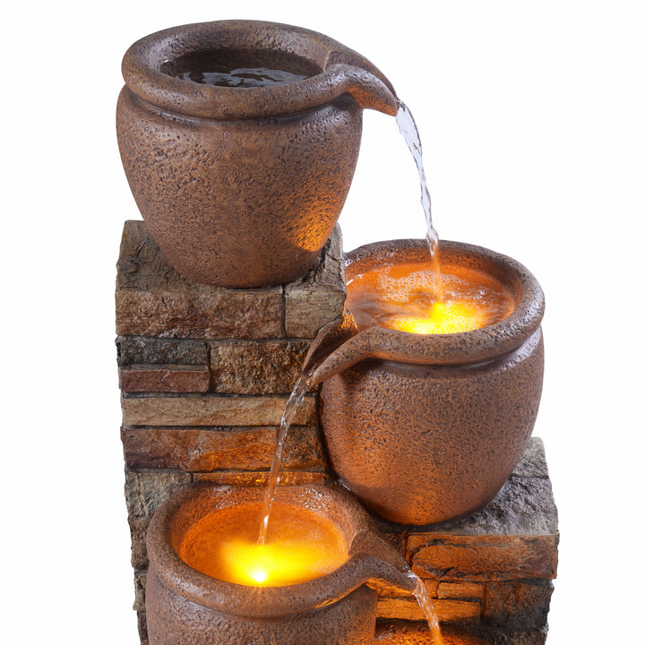 Water flowing down the tiers of a faux terracotta pots of a water fountain