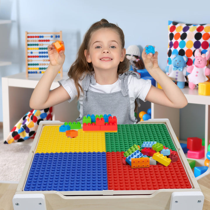 A girl building something on top of building surface with assorted building blocks.