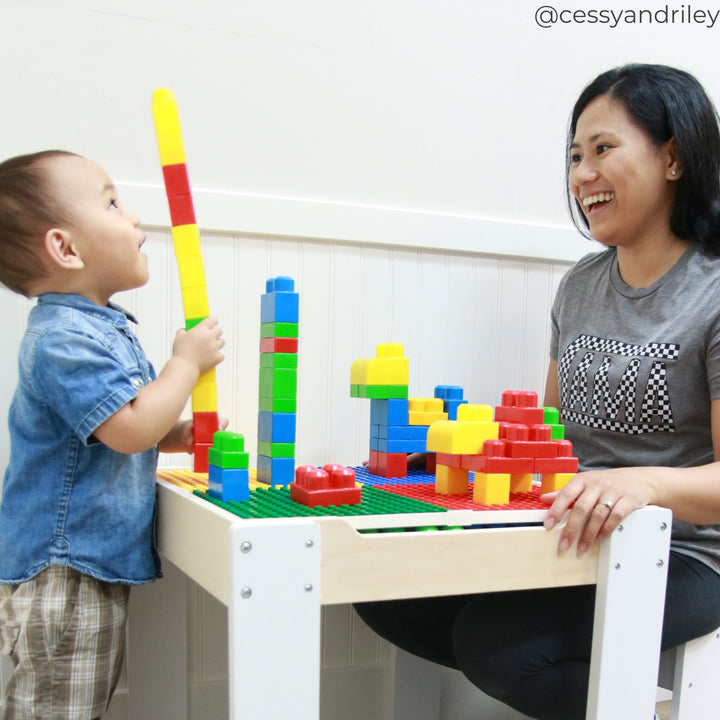 A toddler and mother sitting at a small table building with interlocking blocks