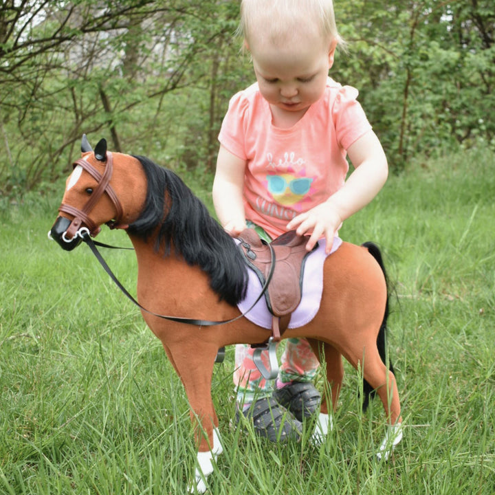 a toddler puts the horse in it's saddle