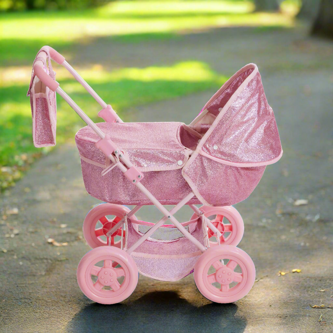 A pink glittery bassinet style stroller is standing in a sunny park